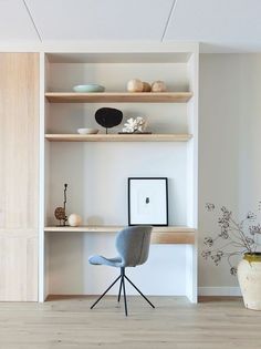 a chair and some shelves with vases on them in a room that has wood flooring