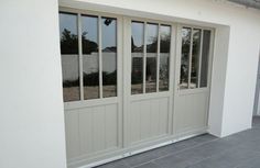 a white building with three windows on each side and one door open to the outside