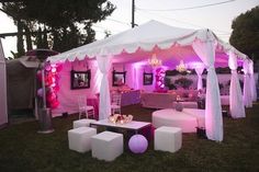 a tent set up with white furniture and pink lighting