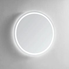 a round mirror is lit up on the wall