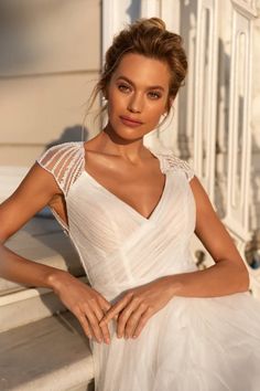 a beautiful woman in a white dress posing for the camera