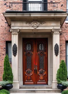 a red door with two black planters in front of it on a brick building