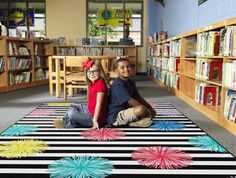 two children sitting on the floor in a library with bookshelves full of books