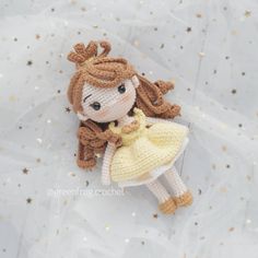 a crocheted doll laying on top of a white sheet with gold glitters