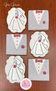 four decorated cookies in the shape of grooms and brides on top of a wooden table