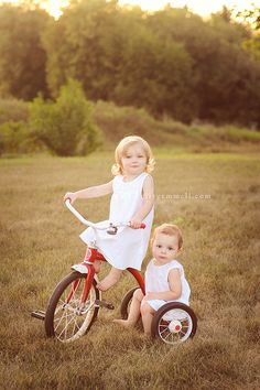 two young children are riding their bikes in the grass