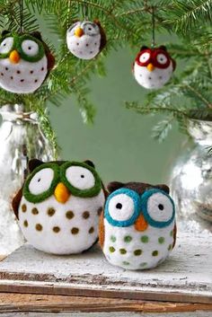 three owls are sitting on a table under a christmas tree with ornaments hanging from the branches