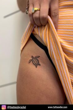 a woman with a small tattoo on her thigh holding onto a yellow and white striped shirt