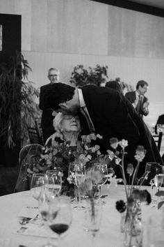 black and white photograph of an elderly couple kissing each other at a formal dinner table