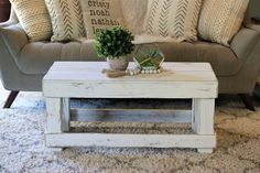 a coffee table sitting on top of a rug in front of a couch with pillows