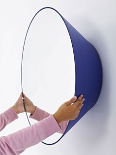 a woman is drawing on the side of a blue and white wall with a marker