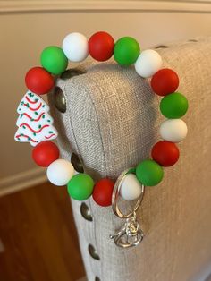 a bracelet with christmas decorations on it sitting on top of a couch next to a keychain