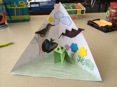 an origami bird on top of a paper pyramid with flowers and butterflies painted on it