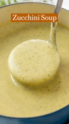 a spoon full of creamy zucchini soup in a blue pot with the title above it