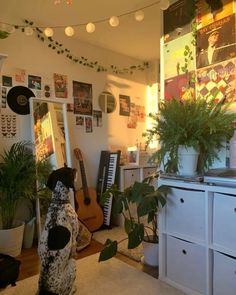 a dog is sitting on the floor in front of a plant and some music equipment