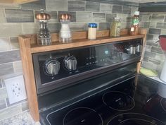 a black stove top oven sitting inside of a kitchen next to a wall mounted spice dispenser