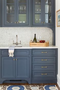 a kitchen with blue cabinetry and white counter tops, gold trim on the cabinets