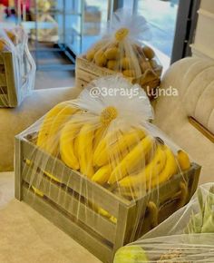 some bananas are wrapped in plastic and sitting on a table next to other fruit boxes