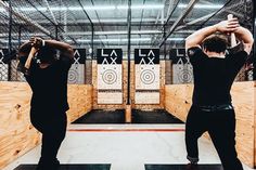 two men in black shirts are practicing archery with their backs to the camera, and one man is holding his hands up