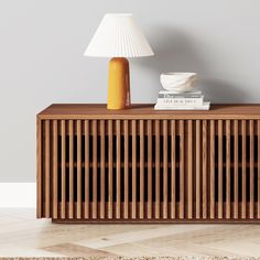 a wooden sideboard with books and a lamp on top