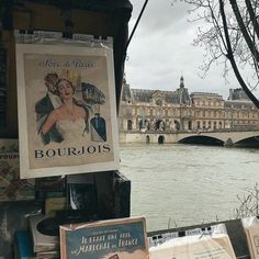 an old poster is hanging on the side of a building next to a body of water