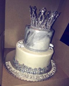 a three tiered cake with silver crown on top