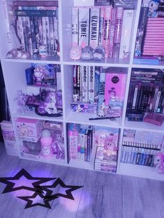 a book shelf filled with lots of books next to a star shaped light on the floor