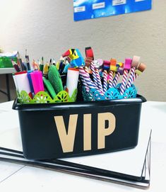 a black container filled with lots of different colored pens and pencils on top of a table