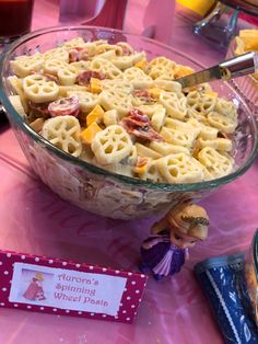 a bowl filled with macaroni and cheese on top of a pink table cloth