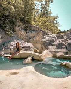 a woman is sitting on rocks in the water