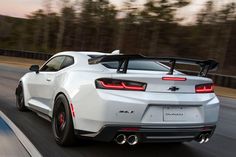 a white chevrolet camaro driving down the road