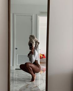 a woman kneeling on the floor in front of a mirror with her legs spread out