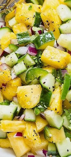 a white plate topped with cucumber and mango salad next to a silver fork