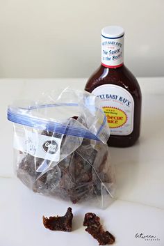 a bottle of ketchup next to some candies in a plastic bag on a table