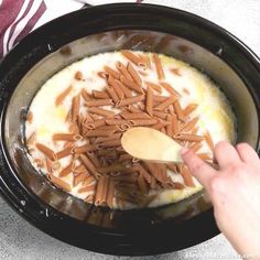 someone is spooning some pasta into the crock pot with brown noodles in it