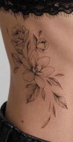 a woman's lower back tattoo with flowers on her stomach and leaves in the middle