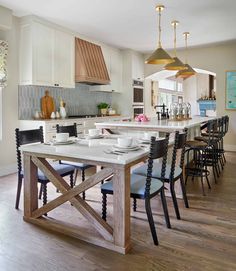 a kitchen table with chairs and plates on it in front of a stove top oven