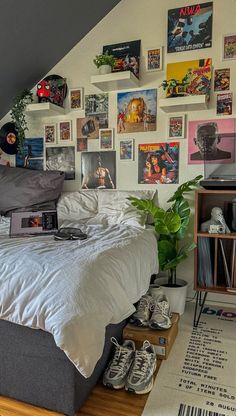 a bedroom with pictures on the wall above the bed and below the bed is a laptop