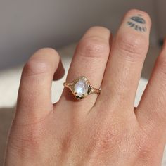 a woman's hand with a ring on it that has a small white stone in the middle