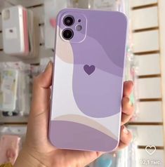 a person holding up a phone case with a heart design on it in front of some shelves