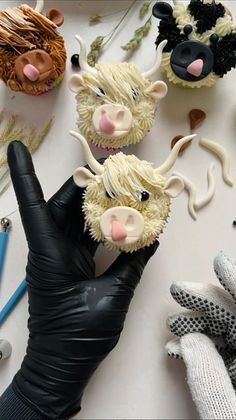 cupcakes decorated to look like farm animals are being held by a gloved hand