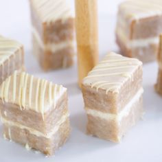 several pieces of cake sitting on top of a white plate next to a wooden stick