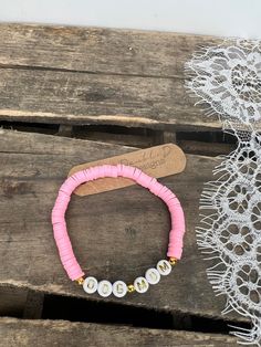 a pink bracelet with two white pearls on it and a lace doily next to it