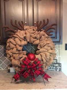 a christmas wreath with reindeer antlers and an ornament on the front door