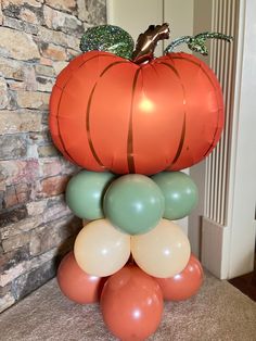 an orange pumpkin and some balloons in front of a brick wall