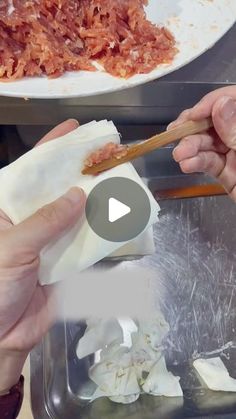 two hands holding chopsticks over food in a container