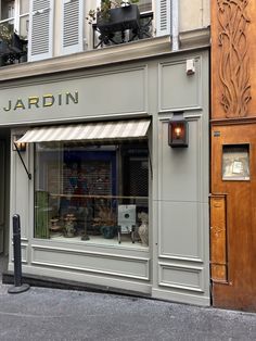 the storefront of jardin in paris is painted gray and features an ornately decorated window