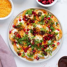 a white plate topped with a pizza covered in toppings next to bowls of cheese and other food