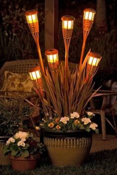 an arrangement of lights in a potted planter with white flowers on the ground