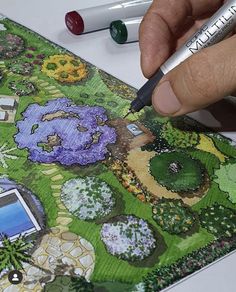 a person is painting a garden scene on a piece of paper with markers and pencils